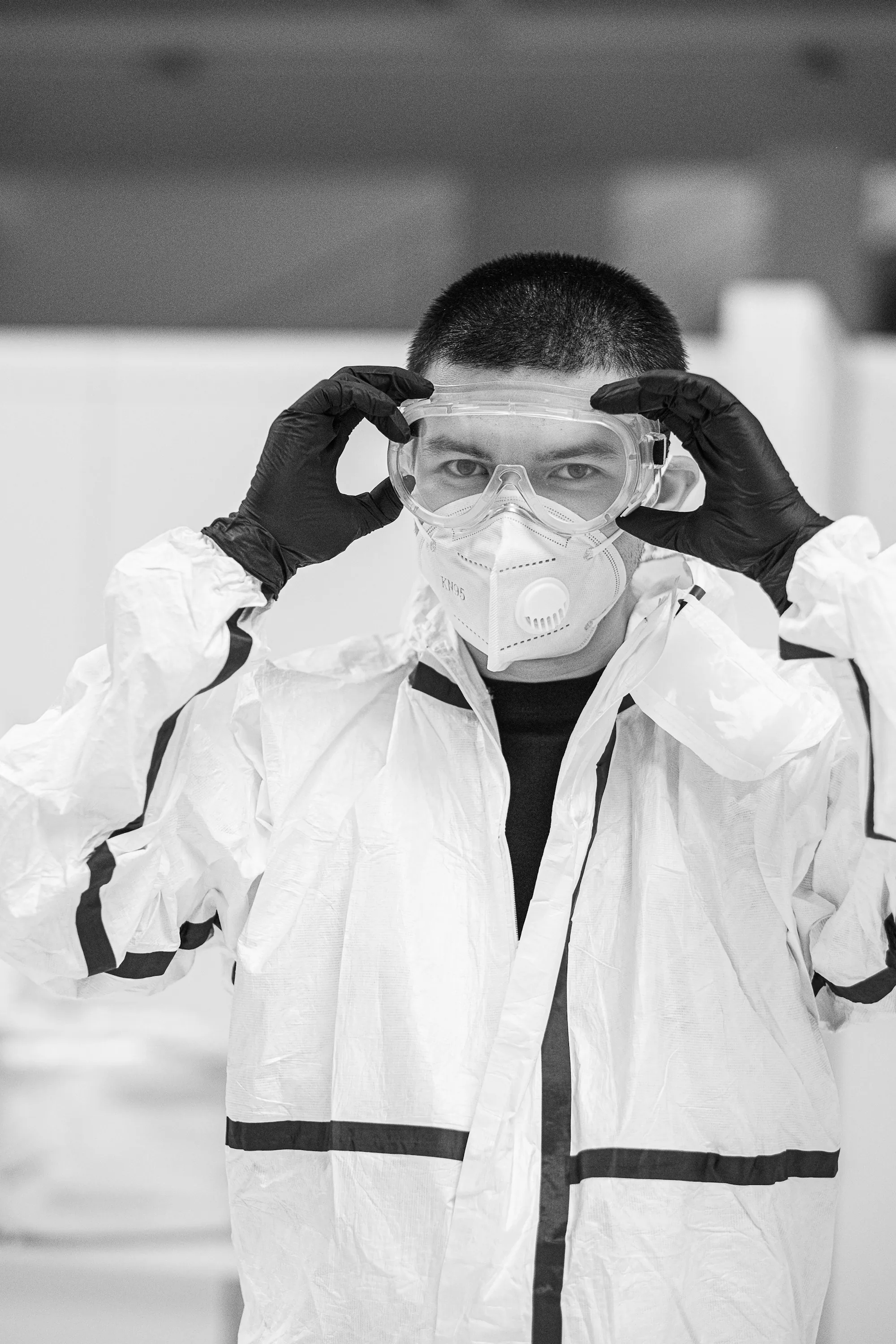 Worker in a protective suit fitting a disposable respirator